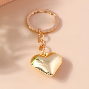 Dettaglio ravvicinato di un ciondolo a cuore dorato lucido con anello in metallo