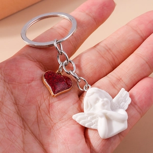 Detail of angel keychain with silver ring, red sequin heart, and white cherub charm