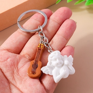 Detailed close-up of a brown guitar charm and white resin angel on a metal keychain ring