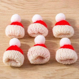 Detailed close-up of mini red and white knitted Christmas hats for DIY craft decor