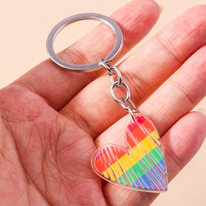 Dettaglio di un portachiavi a cuore arcobaleno in acrilico tenuto in mano per scala