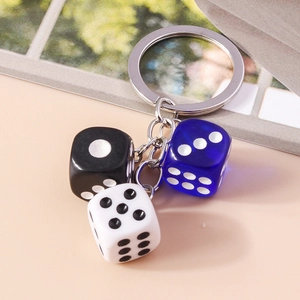 Close-up of acrylic dice keychains in black, white, and blue on a modern magazine background