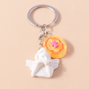 Close-up of cute silver angel keychain with a yellow resin star charm on a beige backdrop
