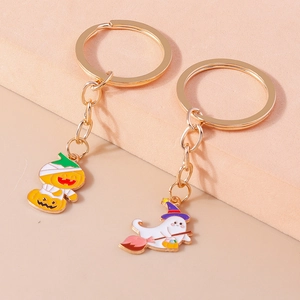 Close-up of golden Halloween keychains featuring pumpkin mummy and ghost on orange background