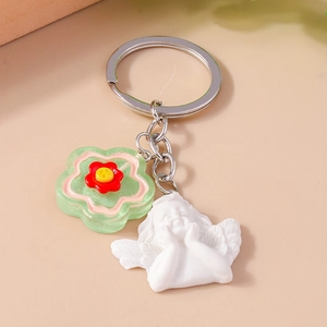 Close-up of cute white angel and translucent green flower charms on a silver keychain