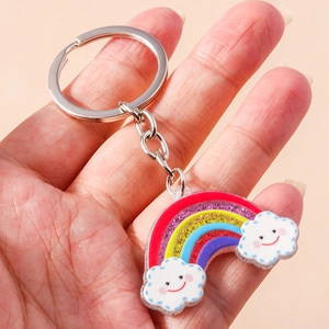 Dettaglio di un portachiavi arcobaleno glitterato con nuvole sorridenti e anello argento