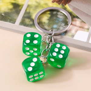 Detailed view of three transparent green acrylic dice with silver metal keychain loop