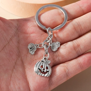 Detail of hand holding vintage silver Halloween pumpkin charms on a metal keychain