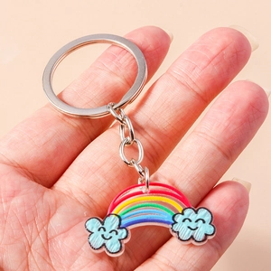Portachiavi con arcobaleno e nuvole blu sorridenti tenuto in mano per mostrare le dimensioni