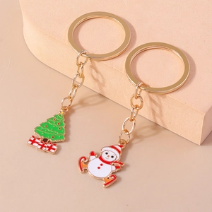Detail view of colorful enamel Christmas snowman and tree keychains on a geometric stand
