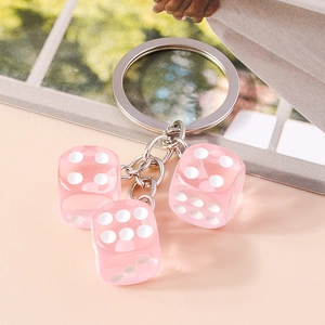 Detail of three translucent pink acrylic dice charms on a silver metal keychain ring