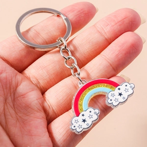Dettaglio di un portachiavi in acrilico con arcobaleno e nuvola tenuto in mano