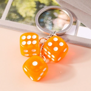 Macro detail of three orange translucent resin dice charms on a silver metal keychain