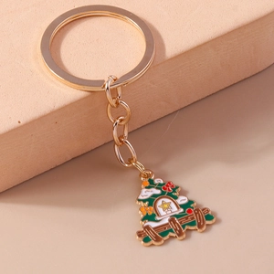 Christmas tree keychain with green enamel pendant and golden metal rings on beige base