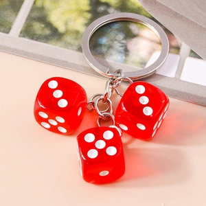 Close-up of three translucent red resin dice pendants on a silver metal keychain