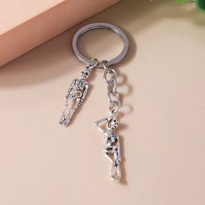 Detail shot of silver metal skeleton pendants and key ring on a minimalist background