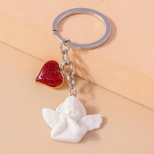 Detail of silver keychain with white resin angel and sparkling red heart pendant