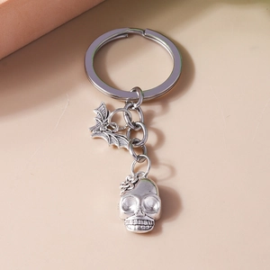 Detailed view of vintage silver metal keychain with skull and bat charms for Halloween