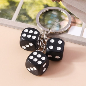 Detailed macro view of three black resin dice pendants with a silver metal keychain ring