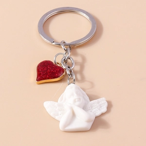 Detail of white resin angel keychain with shiny red glitter heart pendant on metal ring