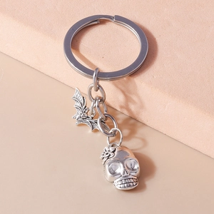Close-up of vintage silver keychain featuring gothic bat and floral skull charms