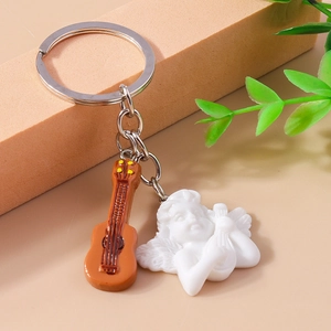 Detail of cute angel and brown guitar charms keychain on a warm decorative setup