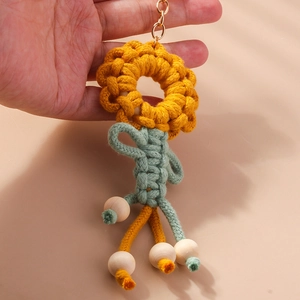 Detail of handmade crochet sunflower keychain with wooden beads and golden ring