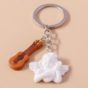 Close-up of a cute white angel charm and a brown guitar pendant on a metal keychain