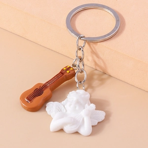 Detail of cute resin angel keychain with a miniature guitar charm on a modern sand base
