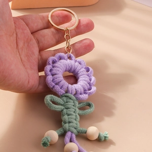 Detailed close-up of handmade purple knitted sunflower keychain with wooden beads and gold ring