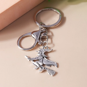 Detailed view of a vintage silver witch on broomstick pendant with a metal keyring