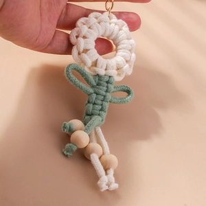 Detail of handmade crochet flower keychain with cream petals and natural wood beads