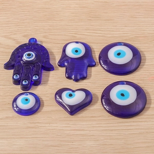 Vue à plat de pendentifs mauvais œil en résine bleue et main de Hamsa sur bois