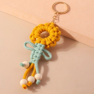 Detail of handmade knit sunflower keychain with yellow petals and natural wood beads