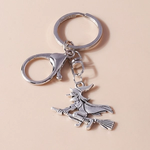 Detail of silver-plated witch riding a broom keychain with lobster clasp and vintage texture