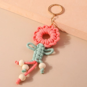 Detail of pink knitted flower keychain with cotton macrame texture and wooden bead