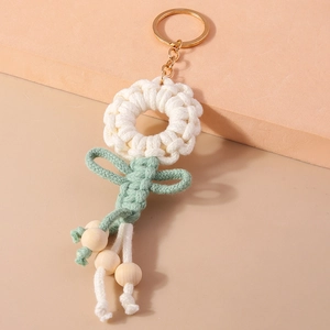 Detail of handmade crochet flower keychain with golden ring and natural wooden beads