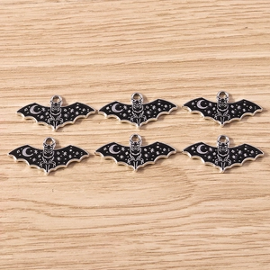 Detail of DIY jewelry charms showing dark enamel bat pendants with moon and star patterns