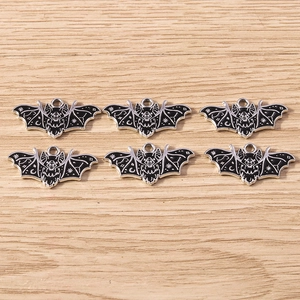 Macro detail of bat-shaped enamel charms with celestial patterns for DIY jewelry making