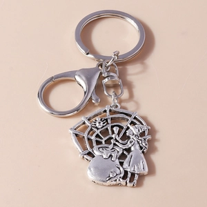Close-up of vintage silver keychain featuring a witch stirring a cauldron on a spiderweb
