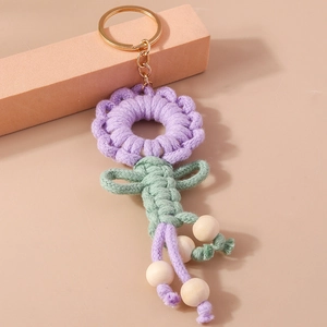 Macro detail of handmade knitted purple flower keychain with wooden beads and gold ring