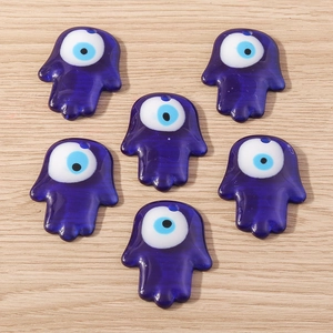 Vue détaillée de six breloques main de Hamsa avec motifs d'œil bleu sur bois
