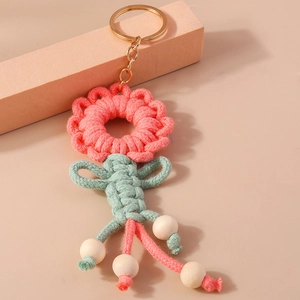 Detail of handmade knit flower keychain with pink petals and green leaf on metal ring