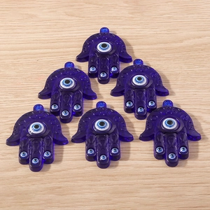 Vue détaillée de pendentifs main de Fatma en résine bleue avec le symbole mauvais œil