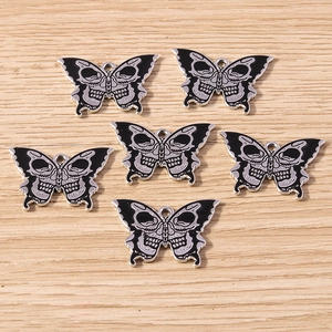 Detail of gothic butterfly charms with skull wing design and black enamel finish