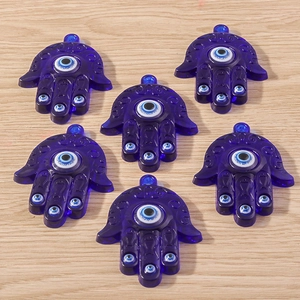 Détail macro de pendentifs Main de Fatma en résine bleue avec motifs mauvais œil pour bijoux