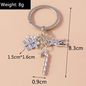 Detailed silver keychain with gift box, candy cane and rabbit charms on beige background