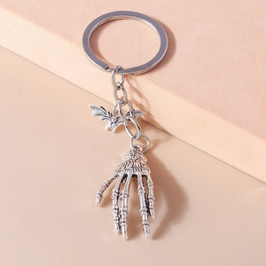 Detail shot of gothic keychain featuring silver metal bat and skeleton hand charms