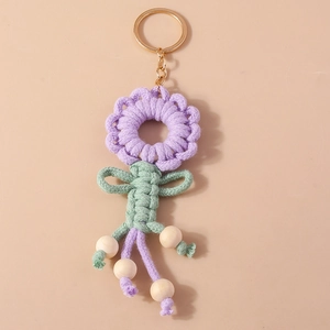 Detail of purple knitted sunflower keychain with green leaves and natural wooden beads