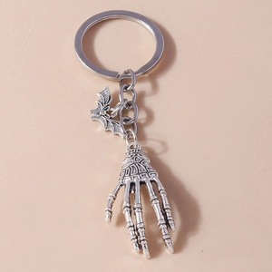 Detail of silver gothic keychain with skeletal hand and bat wing charms for Halloween